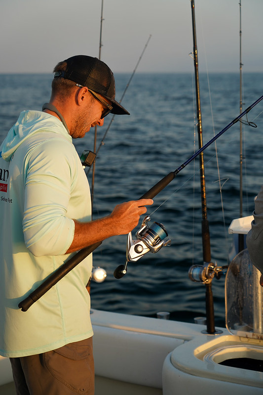 Ryan Morie standing on a fishing boat, holding a fishing rod.