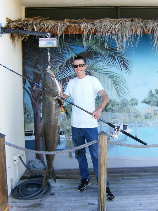 Ryan Morie standing on a dock next to a record-breaking Cobia fish.