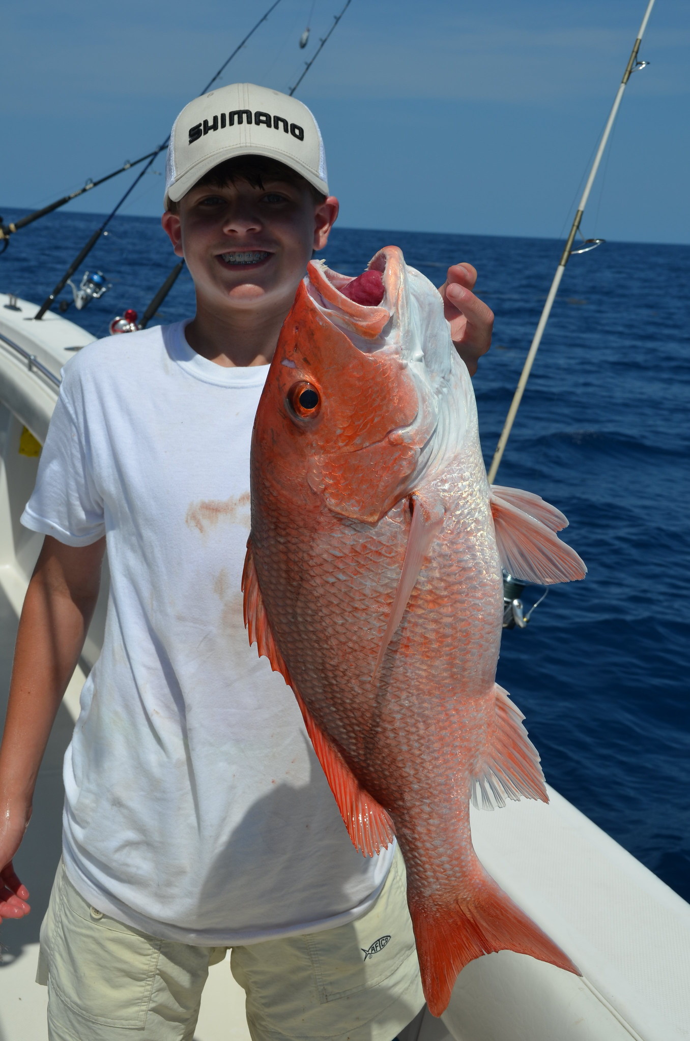 A young angler on a boat, holding a Red snapper.
