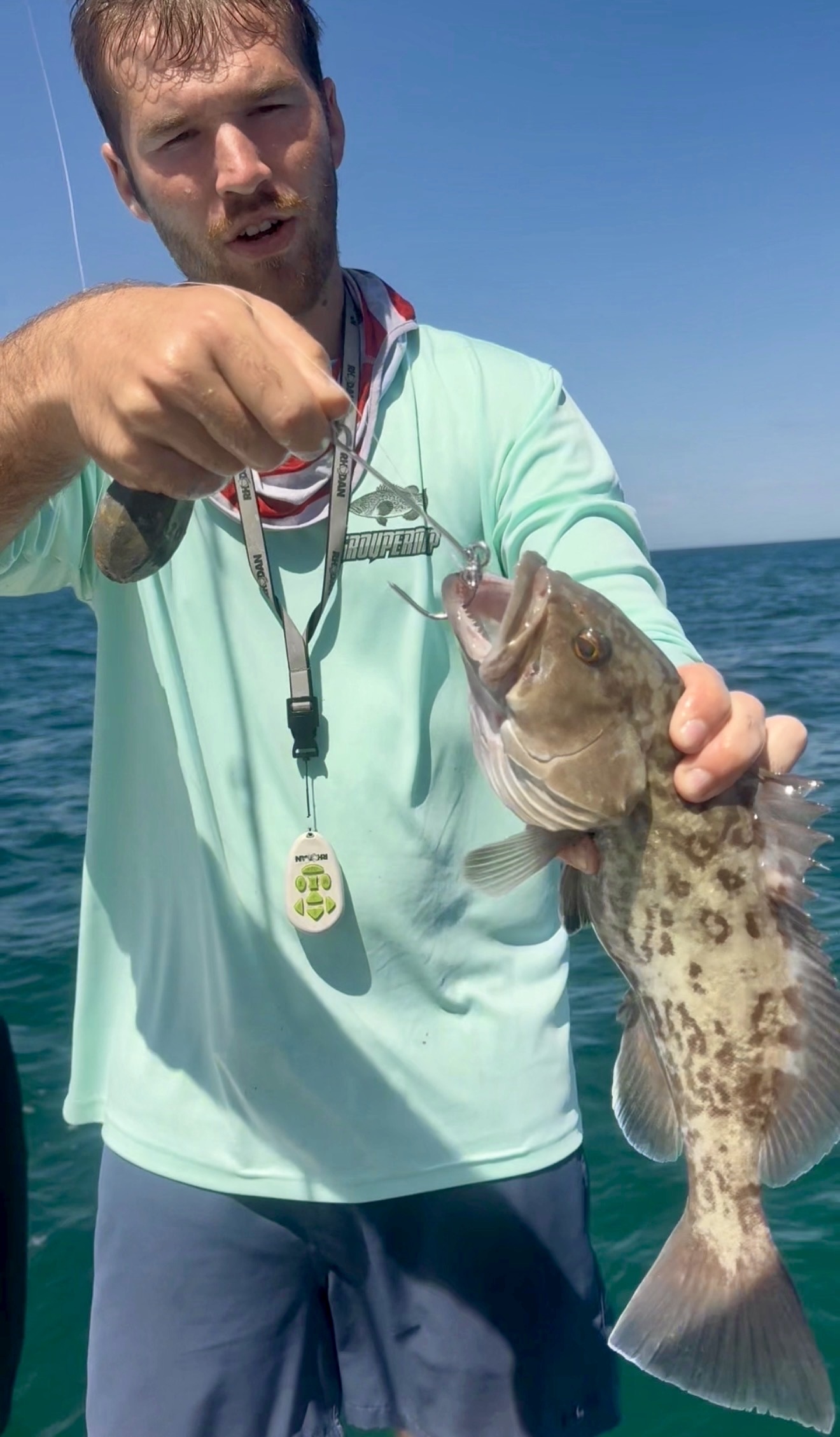 Angler on a boat holding a grouper attached to a Fishsaverpro inverted hook descending device.