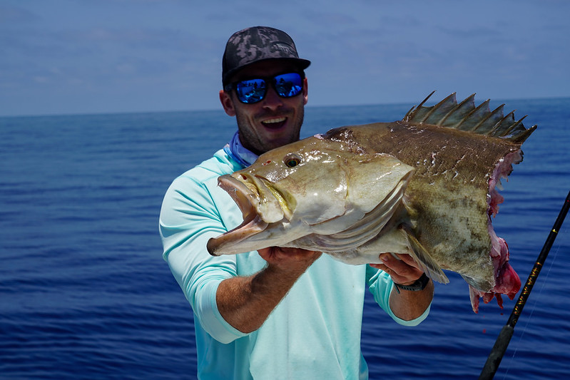 Photo of an angler holding a fish that had half its body eaten by a shark.