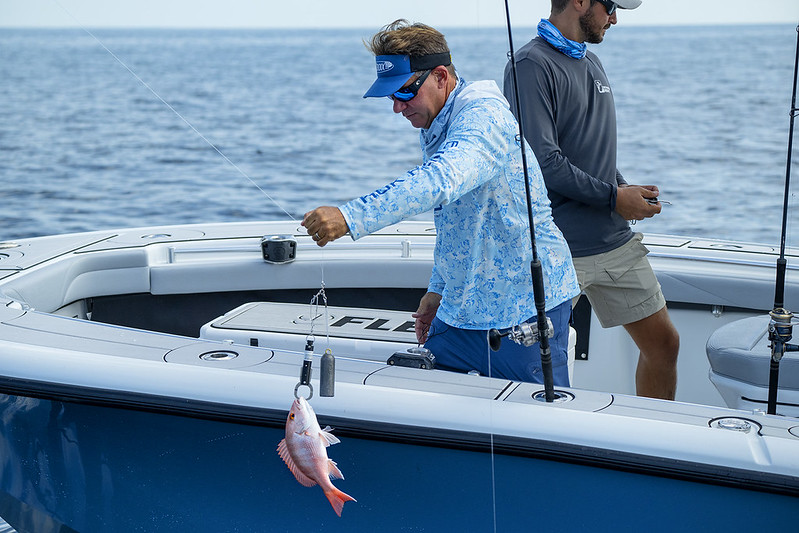 Photo of an angler using a descending device to release a fish off the side of a boat.