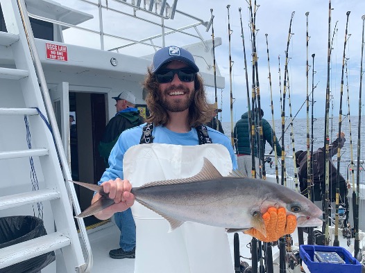 A person holding a fish on a boat.