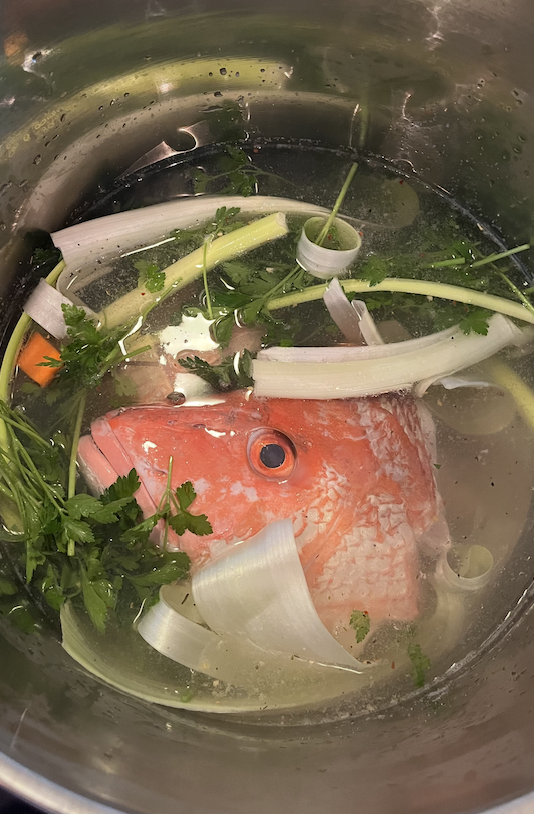 A fish head prepped in a pot of water to make soup.